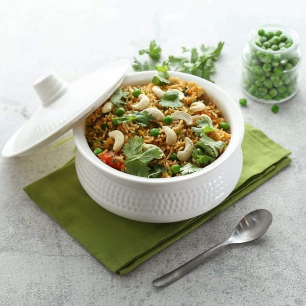 Honest Indian Restaurant's biryani with cashews, peas, and cilantro in a white bowl with a green napkin.